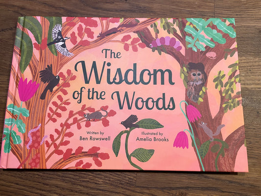 Book titled 'The Wisdom of the Woods' with illustrations on a wooden surface
